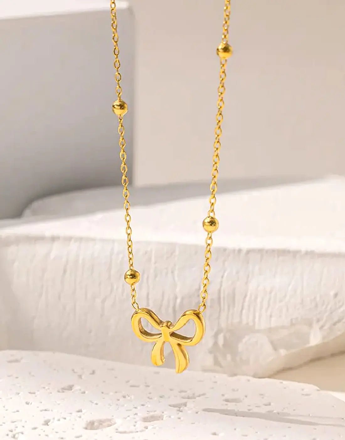 Simple Bowelle Necklace by Glitze Accessories featuring a delicate chain with a small bow pendant.